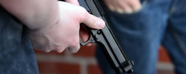 Un hombre sostiene una pistola - Sputnik Mundo