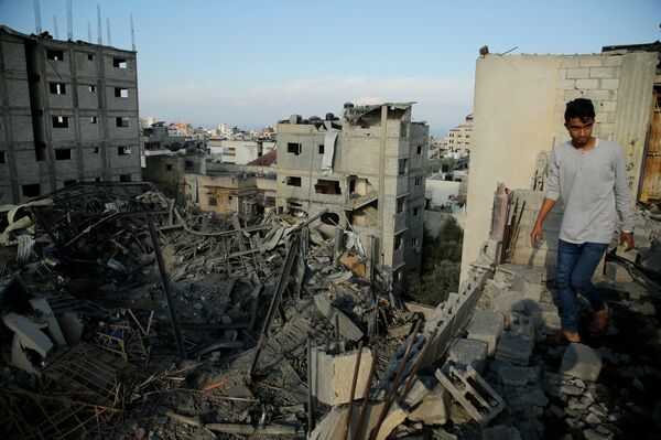 Un hombre camina en las ruinas de una edificación en Gaza - Sputnik Mundo