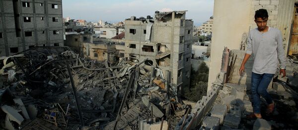 Un hombre camina en las ruinas de una edificación en Gaza - Sputnik Mundo