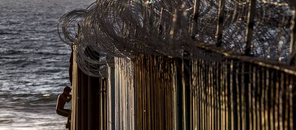 Dos jóvenes se suben al muro de playas de Tijuana después de que el Ejército estadounidense colocara alambre de púas el 13 de noviembre del 2018 - Sputnik Mundo