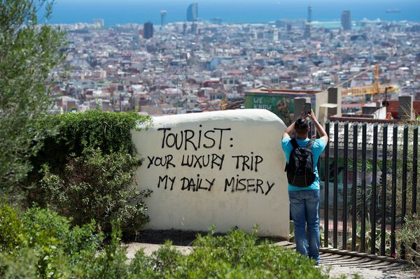 Vista a la ciudad de Barcelona desde el Park Guell, con una inscripción 'Turista: tu viaje de lujo es mi miseria diaria' - Sputnik Mundo