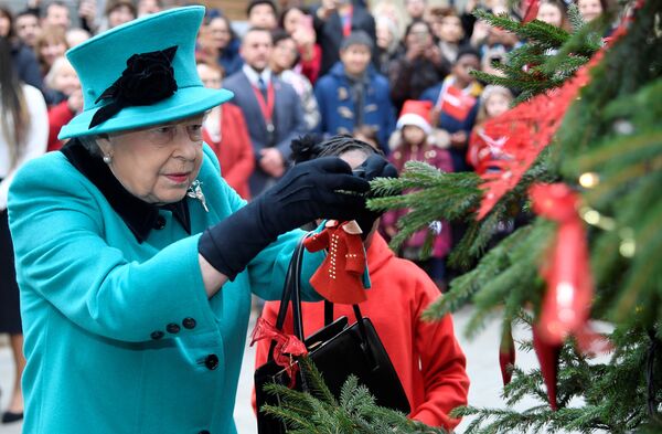 La reina Isabel II, de Reino Unido, coloca un chirimbolo en el árbol de Navidad de la organización benéfica infantil Coram, en Londres - Sputnik Mundo