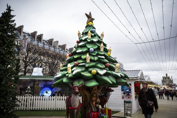 Un hombre pasa junto a un árbol de Navidad en un mercado de Navidad en el Jardin des Tuilleries (Jardín Tuilleries), en París - Sputnik Mundo