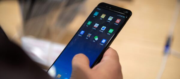 Un hombre con un teléfono de Xiaomi en Pekín - Sputnik Mundo