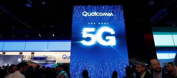 La gente pasa al lado de una pantalla que promociona la conectividad 5G en el stand de Qualcomm - Sputnik Mundo