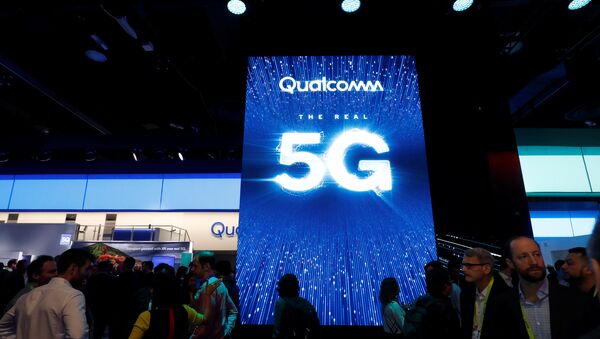 La gente pasa al lado de una pantalla que promociona la conectividad 5G en el stand de Qualcomm - Sputnik Mundo