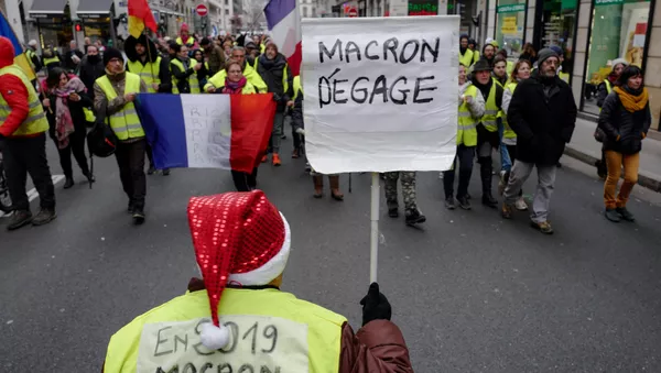 Los 'chalecos amarillos' protestan con el cartel 'Macron, largate!' en París