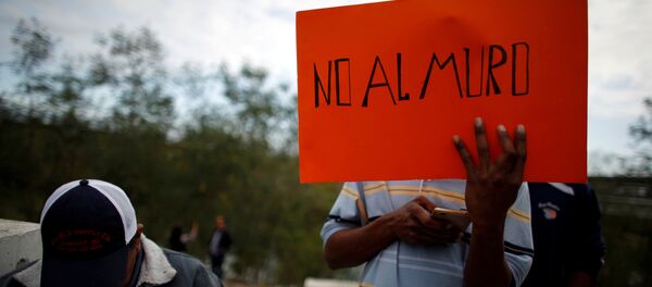 Un inmigrante sostiene una pancarta que dice 'No al muro' - Sputnik Mundo