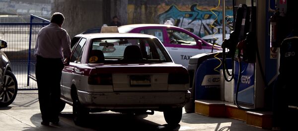 Taxista al terminar de llenar su tanque de gasolina. La mayoría de las filas están llena de taxistas Taxista al terminar de llenar su tanque de gasolina. La mayoría de las filas están llena de taxistas - Sputnik Mundo