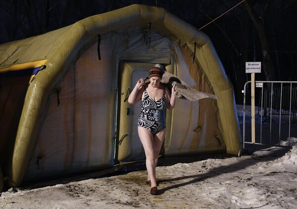 Una mujer se prepara para participar en las celebraciones de la Epifanía en Moscú - Sputnik Mundo