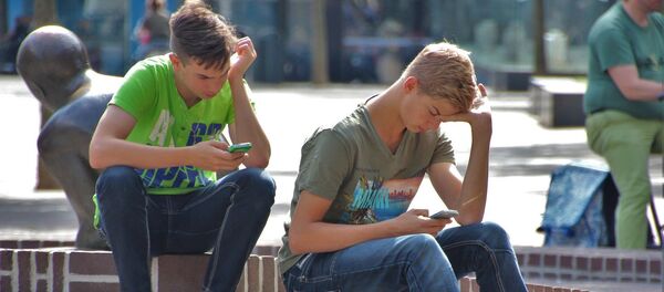 Jóvenes con sus celulares en una plaza - Sputnik Mundo