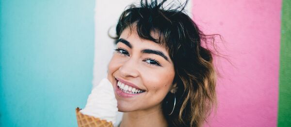 Una chica sonríe mientras come un helado - Sputnik Mundo