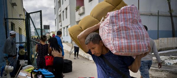 Un hombre carga sus pertenencias a un bus en La Habana después del tornado del 27 de enero - Sputnik Mundo