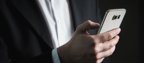 Hombre sostiene un teléfono - Sputnik Mundo