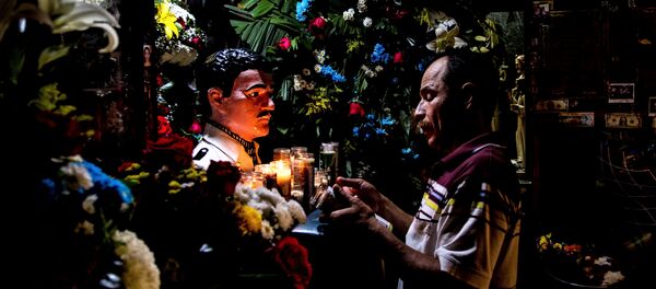 Culiacán, Sinaloa. Hombre reza frente a la imagen de Jesús Malverde en su capilla. - Sputnik Mundo