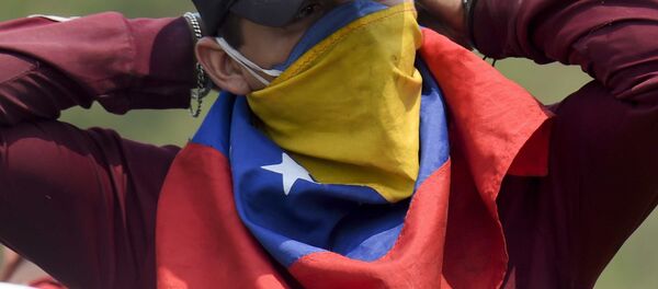 Un manifestante con la bandera de Venezuela en su cara - Sputnik Mundo