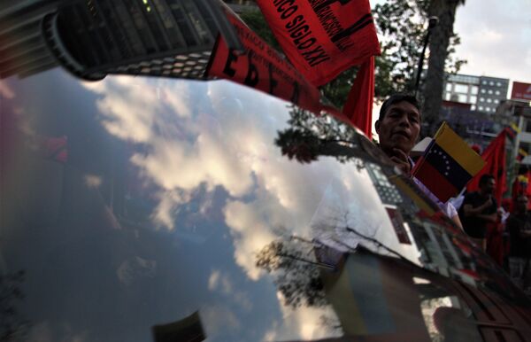 Hombre con la bandera de Venezuela se refleja en el vidrio de un auto durante una marcha en Ciudad de México Hombre con la bandera de Venezuela se refleja en el vidrio de un auto durante una marcha en Ciudad de México - Sputnik Mundo