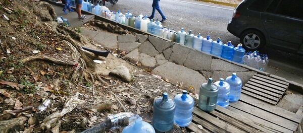 Venezolanos rellenan botellas de agua durante apagón en Caracas - Sputnik Mundo