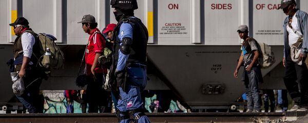 Seguridad privada vigila a migrantes frente a un tren de carga. En la ruta migrante se encontraron al menos cuatro de estas empresas dedicadas a la custodia de las vías, que también ejercen funciones de migración y seguridad pública. - Sputnik Mundo