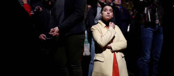 Una mujer se pone de rodillas entre la multitud que observa consternada el incendio de Notre Dame - Sputnik Mundo
