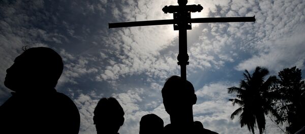 Un hombre sostiene una cruz durante un entierro masivo de víctimas en Sri Lanka - Sputnik Mundo