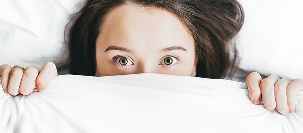 Mujer se asoma por las sábanas de una cama - Sputnik Mundo