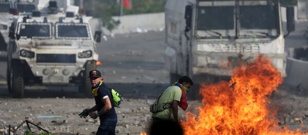 Seguidores de la oposición venezolana caminan en frente de un vehículo militar durante un enfrentamiento con las fuerzas de seguridad - Sputnik Mundo
