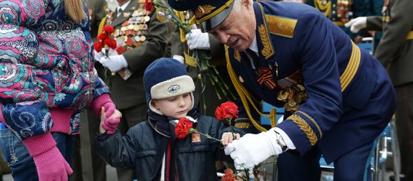 Un niño regala claveles rojos a un veterano durante las celebraciones del Día de la Victoria de 2017, en el Parque de la Victoria en Moscú - Sputnik Mundo