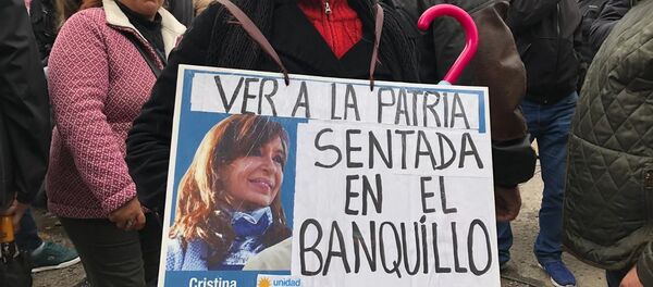 Una mujer sostiene un cartel en apoyo a Cristina Fernández durante el juicio oral en su contra - Sputnik Mundo