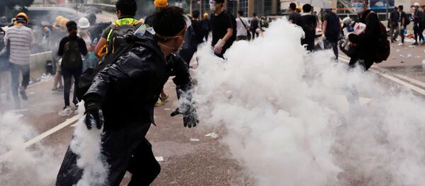 Un manifestante lanza una lata de gas lacrimógeno durante una manifestación contra un proyecto de la ley de extradición en Hong Kong, China. Un manifestante lanza una lata de gas lacrimógeno durante una manifestación contra un proyecto de la ley de extradición en Hong Kong, China. - Sputnik Mundo