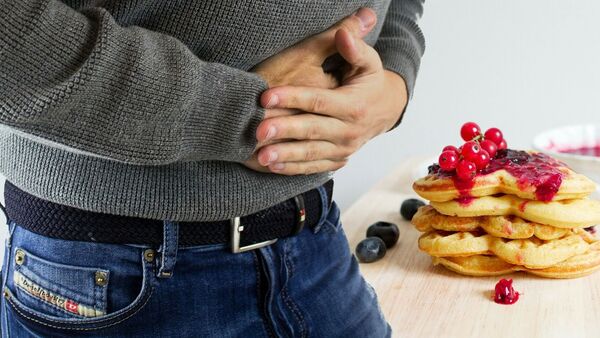 Un hombre sostiene manos sobre su estómago - Sputnik Mundo