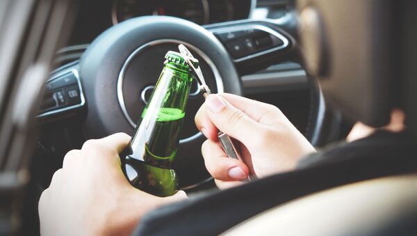 Persona abriendo una botella de alcohol en un auto - Sputnik Mundo