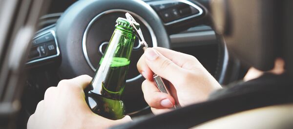 Persona abriendo una botella de alcohol en un auto - Sputnik Mundo