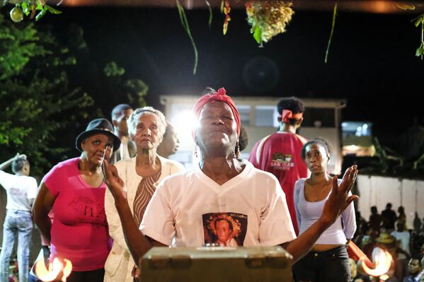 Una mujer reza frente a la estatuilla de San Juan durante la celebración del Día de San Juan Bautista en Curiepe. - Sputnik Mundo