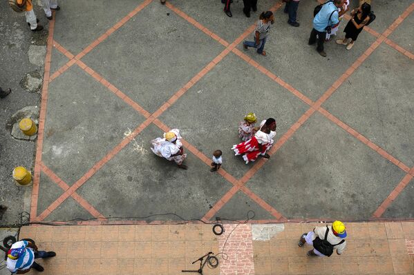 Una madre camina junto a su hija frente a la Iglesia del pueblo durante la celebración de la misa del Día de San Juan Bautista en Curiepe. - Sputnik Mundo