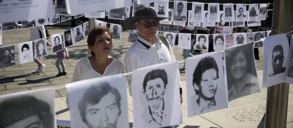 Una pareja mira las imágenes de personas desaparecidas - Sputnik Mundo