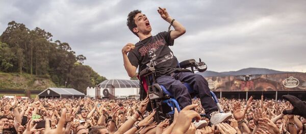 Decenas de jóvenes levantan la silla de ruedas de un muchacho con parálisis cerebral para que pudiera ver un concierto en el festival  Resurrection Fest - Sputnik Mundo