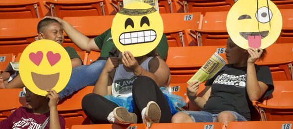 Болельщики с масками-эмодзи на трибуне перед началом матча между студенческими командами в Гонолулу - Sputnik Mundo