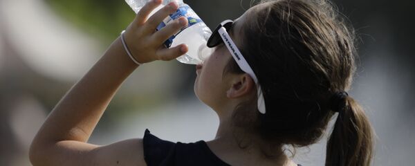 Una joven bebe agua durante la ola de calor que azotó Europa el verano de 2019 (archivo) - Sputnik Mundo