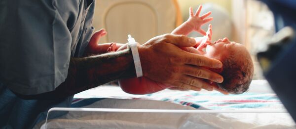 Un doctor sostiene a un bebé recién nacido - Sputnik Mundo