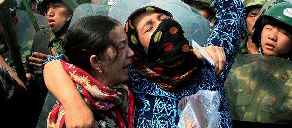 Dos mujeres uigures en frente de los policías chinos en la provincia de Sinkiang - Sputnik Mundo