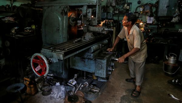 Un trabajador en un torno mientras fabrica piezas de repuesto de cajas de cambios para automóviles en un taller en Calcuta, la India. - Sputnik Mundo