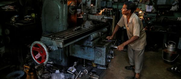 Un trabajador en un torno mientras fabrica piezas de repuesto de cajas de cambios para automóviles en un taller en Calcuta, la India. - Sputnik Mundo