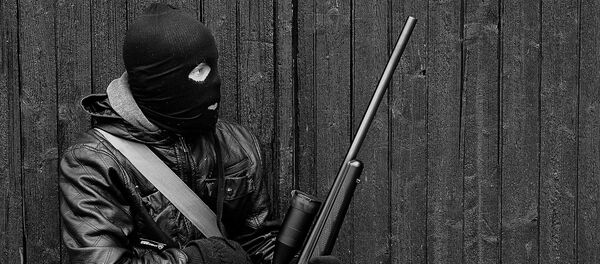 Un hombre en un pasamontañas con un arma - Sputnik Mundo