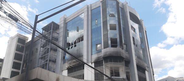 El edificio de la Contraloría General de Ecuador, en Quito, luego de que grupos de encapuchados, lo atacaron y prendieron fuego a varias de sus oficinas. Los vidrios rotos, el olor a humo, el color negruzco de sus paredes, son los vestigios del último fin de semana, en que la violencia se apoderó de Quito, en medio de las protestas por el incremento de los precios de los combustibles. - Sputnik Mundo