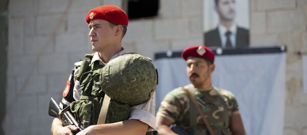Un soldado ruso y otro sirio ante el retrato del presidente Bashar Asad - Sputnik Mundo