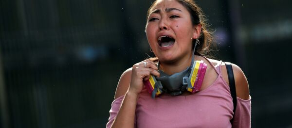 Una mujer chilena corre durante las protestas en Santiago - Sputnik Mundo