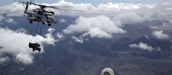 Un helicóptero realiza un repostaje aéreo mientras carga un todoterreno - Sputnik Mundo