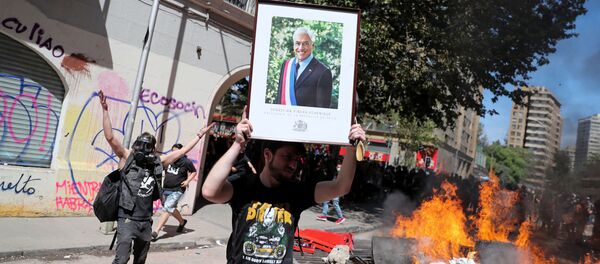 Un manifestante con la imagen del presidente chileno Sebastián Piñera - Sputnik Mundo