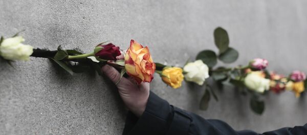 Un hombre coloca una flor en una grieta del Muro de Berlín - Sputnik Mundo